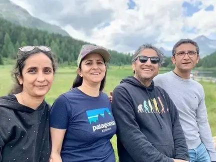Four friends smiling in a mountain landscape with a lake in the background.