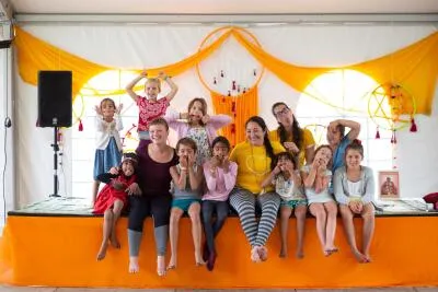 A group of adults and children making funny faces and poses while sitting on a stage.