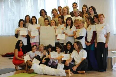 A group of yoga students and instructors posing for a photo with certificates.