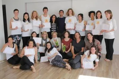 A large group of smiling adults in a studio, many holding certificates, posing for a group photo.