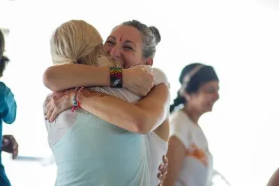 Two women hugging and smiling, with one wearing a wristband and a bindi.