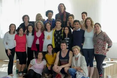 A large group of people smiling and posing for a group photo in a yoga or meditation studio.