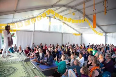 A large group of people in a tent listening to an instructor speaking on a stage.