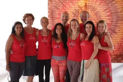 A group of nine people, mostly women, smiling and standing together in red shirts.