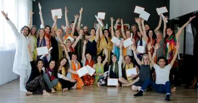 A large group of people smiling and raising their hands, with many holding up certificates in a celebratory group photo.