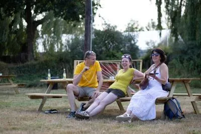 Three people smiling and sitting at a picnic table outdoors.