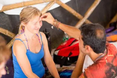 A man touching a smiling woman's forehead, possibly in a spiritual or ceremonial gesture.