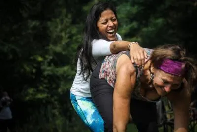Two women laughing heartily in a playful or exercise setting.