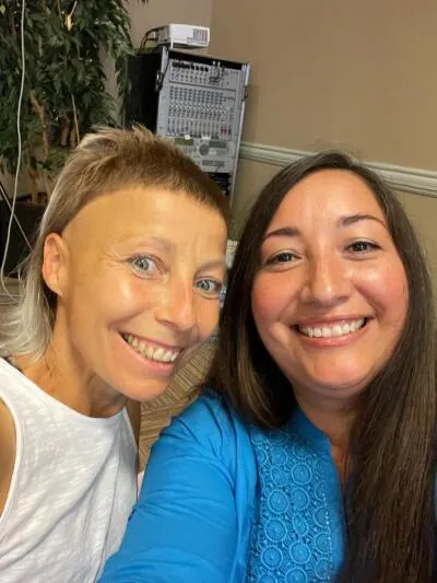 Two smiling women taking a selfie, with professional audio equipment in the background.