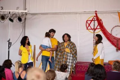 A group of people on a stage, with a man holding a child, in front of an audience.