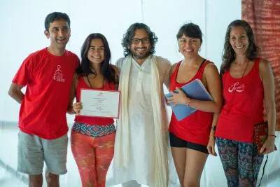 A group of five people, including an instructor in a white tunic and a student with a certificate, smiling for a group photo.