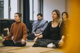 A group of people sitting cross-legged and meditating during a yoga class.